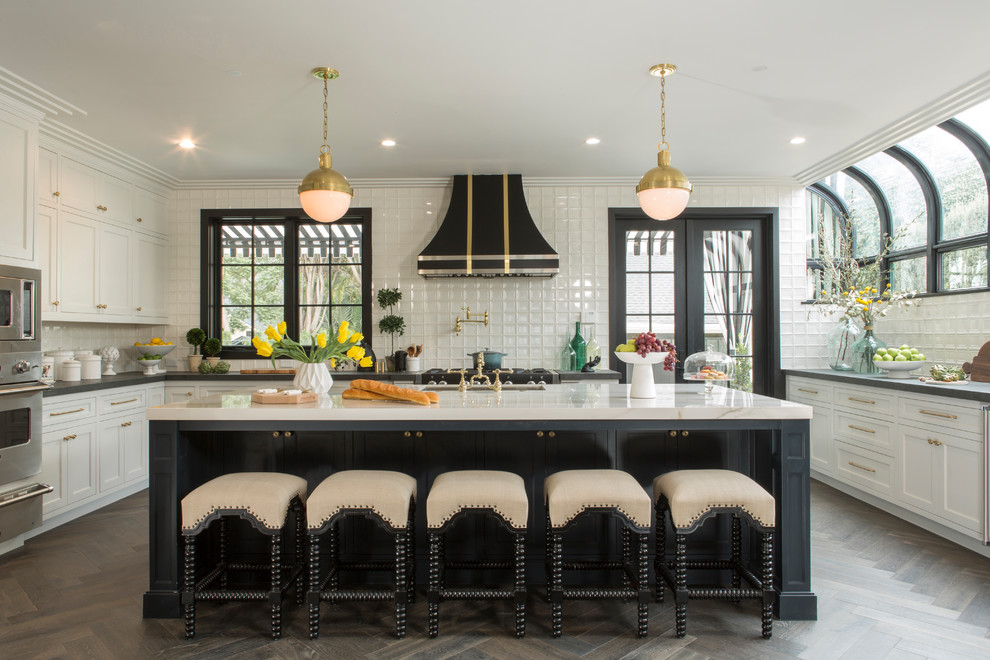 Eclectic u-shaped eat-in kitchen in Los Angeles with an undermount sink, shaker cabinets, white splashback, stainless steel appliances, dark hardwood floors and with island.