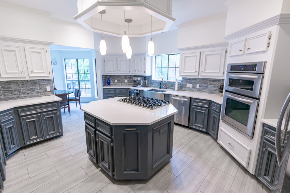 Mid-sized transitional u-shaped ceramic tile and gray floor enclosed kitchen photo in Austin with a farmhouse sink, recessed-panel cabinets, white cabinets, quartzite countertops, blue backsplash, glass tile backsplash, stainless steel appliances, an island and white countertops