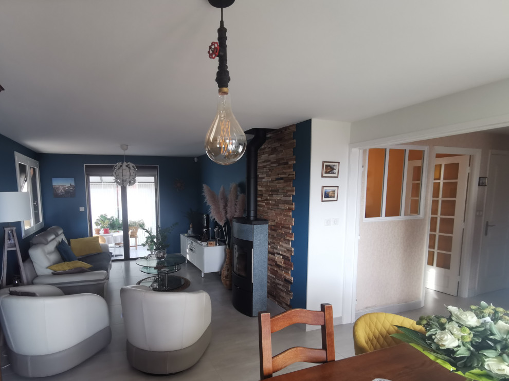 Imagen de salón abierto minimalista de tamaño medio con paredes azules, suelo de baldosas de cerámica, estufa de leña y suelo gris