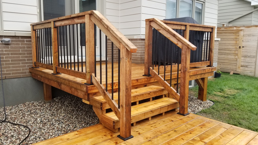 Mid-sized modern backyard and ground level deck in Ottawa with no cover and mixed railing.