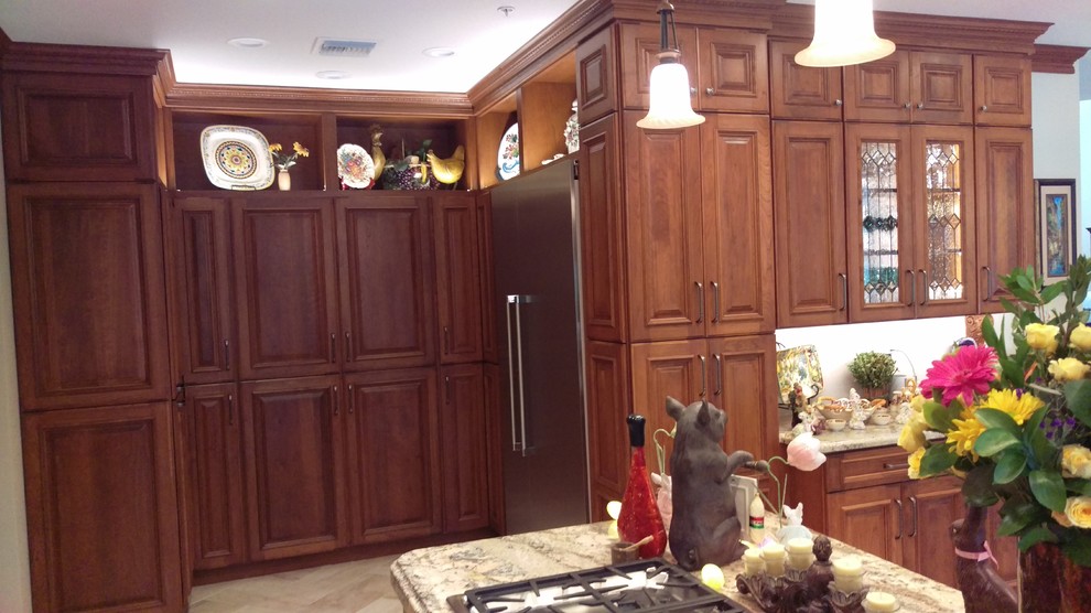 Inspiration for a large mediterranean u-shaped kitchen pantry in Phoenix with an undermount sink, raised-panel cabinets, brown cabinets, granite benchtops, stainless steel appliances, marble floors, with island and beige floor.