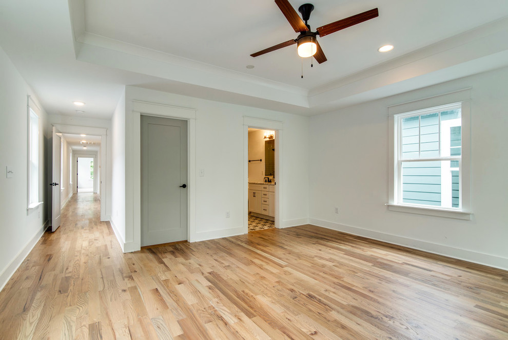 This is an example of a large transitional master bedroom in Nashville with white walls, light hardwood floors, no fireplace and beige floor.