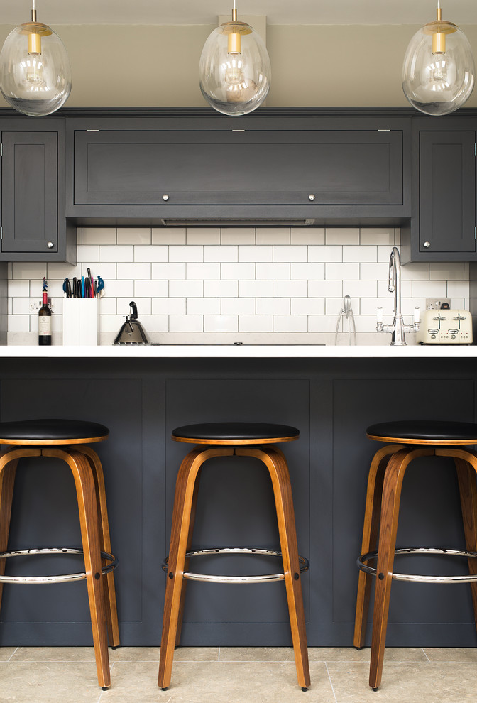 Inspiration for an industrial open plan kitchen in London with shaker cabinets, dark wood cabinets, white splashback, ceramic splashback, black appliances and with island.