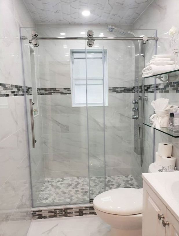 Inspiration for a mid-sized contemporary 3/4 bathroom in New York with raised-panel cabinets, white cabinets, an alcove shower, a two-piece toilet, gray tile, marble, grey walls, an integrated sink, a sliding shower screen, white benchtops, a single vanity and a built-in vanity.
