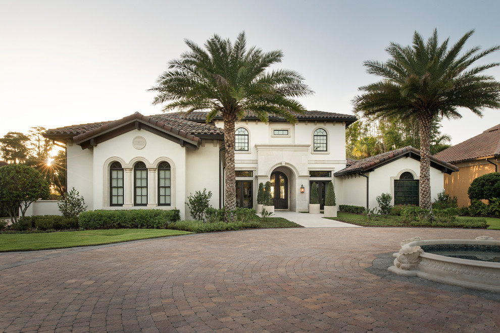 This is an example of a mediterranean two-storey beige house exterior in Orlando with a gable roof and a tile roof.