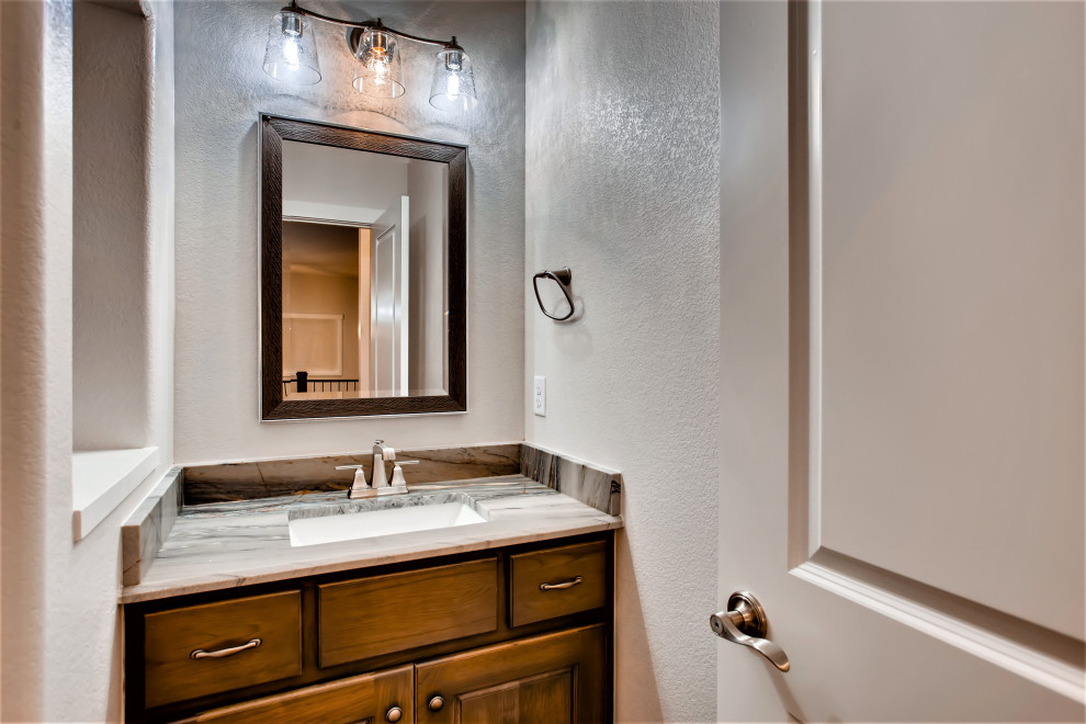 Mid-sized arts and crafts powder room in Denver with raised-panel cabinets, medium wood cabinets, beige walls, an undermount sink, granite benchtops, grey benchtops and a built-in vanity.
