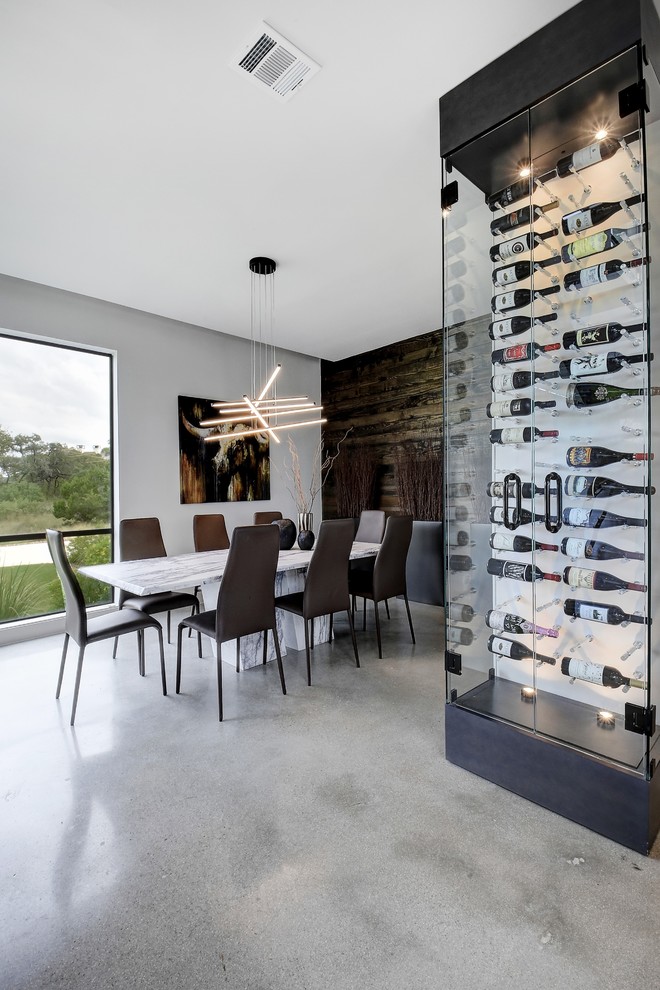 Photo of a mid-sized contemporary wine cellar in Austin with concrete floors, display racks and grey floor.