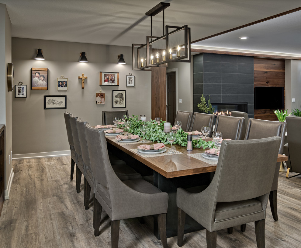 Photo of a large contemporary open plan dining in Minneapolis with grey walls, vinyl floors, a standard fireplace, a tile fireplace surround and multi-coloured floor.
