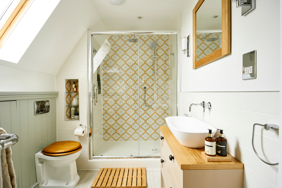 Inspiration for a small traditional master bathroom in Sussex with flat-panel cabinets, beige cabinets, an open shower, a one-piece toilet, multi-coloured tile, ceramic tile, white walls, ceramic floors, a trough sink, wood benchtops, beige floor, a sliding shower screen and beige benchtops.