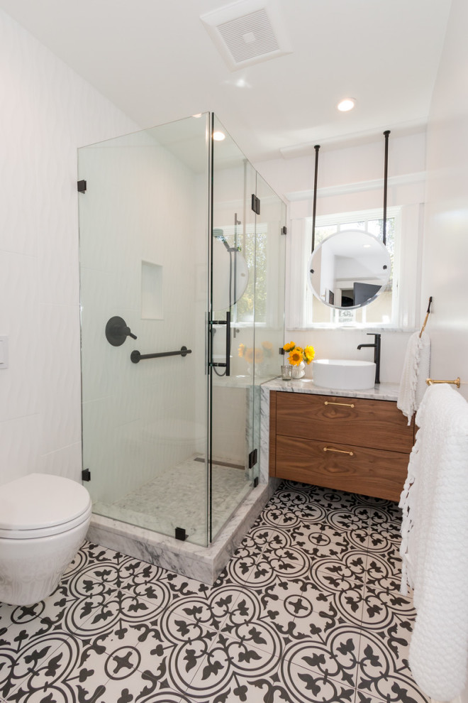 Photo of a small eclectic 3/4 bathroom in San Francisco with flat-panel cabinets, medium wood cabinets, a corner shower, a wall-mount toilet, white tile, porcelain tile, white walls, porcelain floors, a vessel sink, marble benchtops, black floor, a hinged shower door, white benchtops, a niche, a single vanity and a floating vanity.