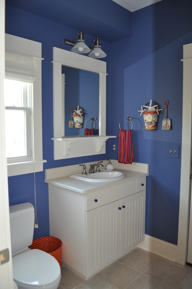 Photo of a small beach style 3/4 bathroom in Other with shaker cabinets, white cabinets, a claw-foot tub, a two-piece toilet, white tile, ceramic tile, beige walls, ceramic floors, a drop-in sink and solid surface benchtops.
