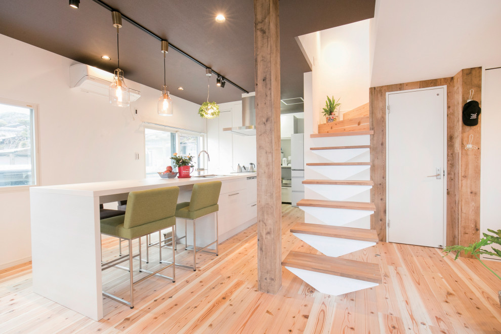 Inspiration for a country single-wall eat-in kitchen in Fukuoka with an integrated sink, flat-panel cabinets, white cabinets, laminate benchtops, white splashback, stainless steel appliances, light hardwood floors, a peninsula, white benchtop and wallpaper.
