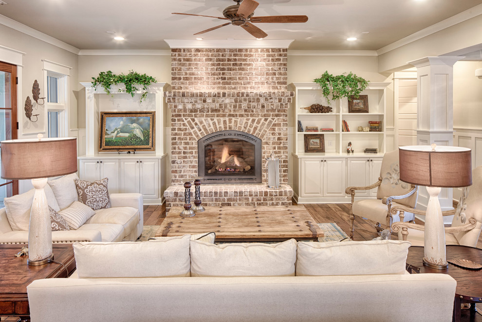 Design ideas for a mid-sized traditional open concept living room in Charleston with beige walls, medium hardwood floors, a standard fireplace, a brick fireplace surround and no tv.