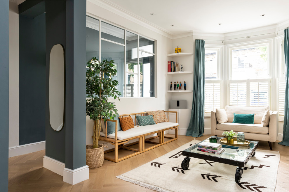 Photo of a medium sized eclectic formal enclosed living room feature wall in London with blue walls, light hardwood flooring, no fireplace, no tv and beige floors.