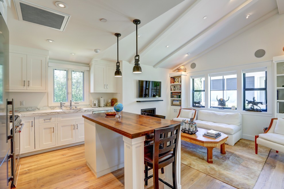 This is an example of a small country l-shaped open plan kitchen in San Francisco with an undermount sink, flat-panel cabinets, white cabinets, wood benchtops, white splashback, marble splashback, stainless steel appliances and with island.