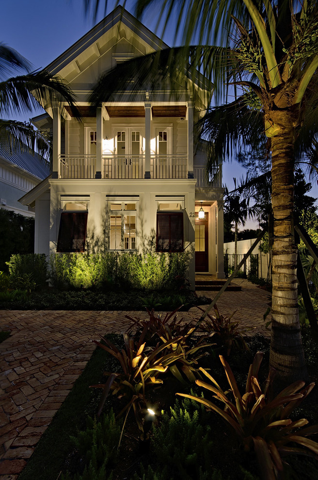 This is an example of a mid-sized tropical two-storey white house exterior in Miami with a gable roof, wood siding and a metal roof.