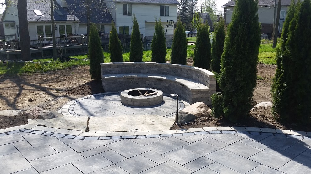 Photo of a large modern backyard patio in Detroit with a fire feature, brick pavers and no cover.