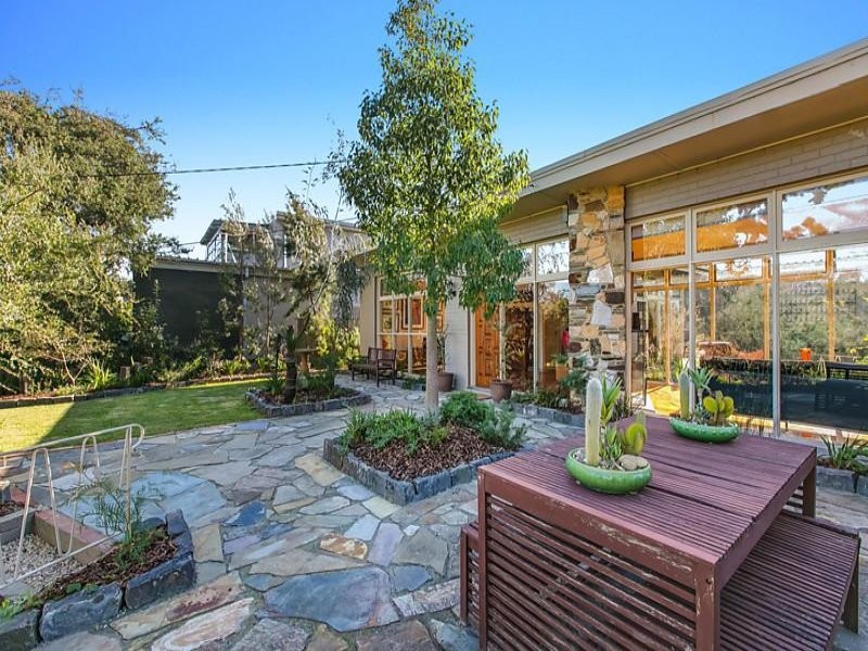 Photo of a mid-sized and australian native midcentury front yard partial sun xeriscape in Melbourne with natural stone pavers.
