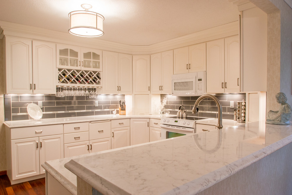 Example of a transitional u-shaped medium tone wood floor eat-in kitchen design in Cedar Rapids with raised-panel cabinets, white cabinets, quartz countertops, white appliances, subway tile backsplash and gray backsplash