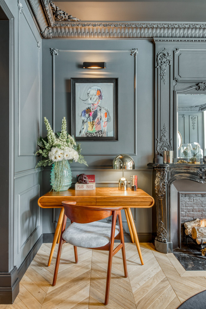 Inspiration for an eclectic study room in Paris with grey walls, light hardwood floors, a standard fireplace, a brick fireplace surround, a freestanding desk and beige floor.