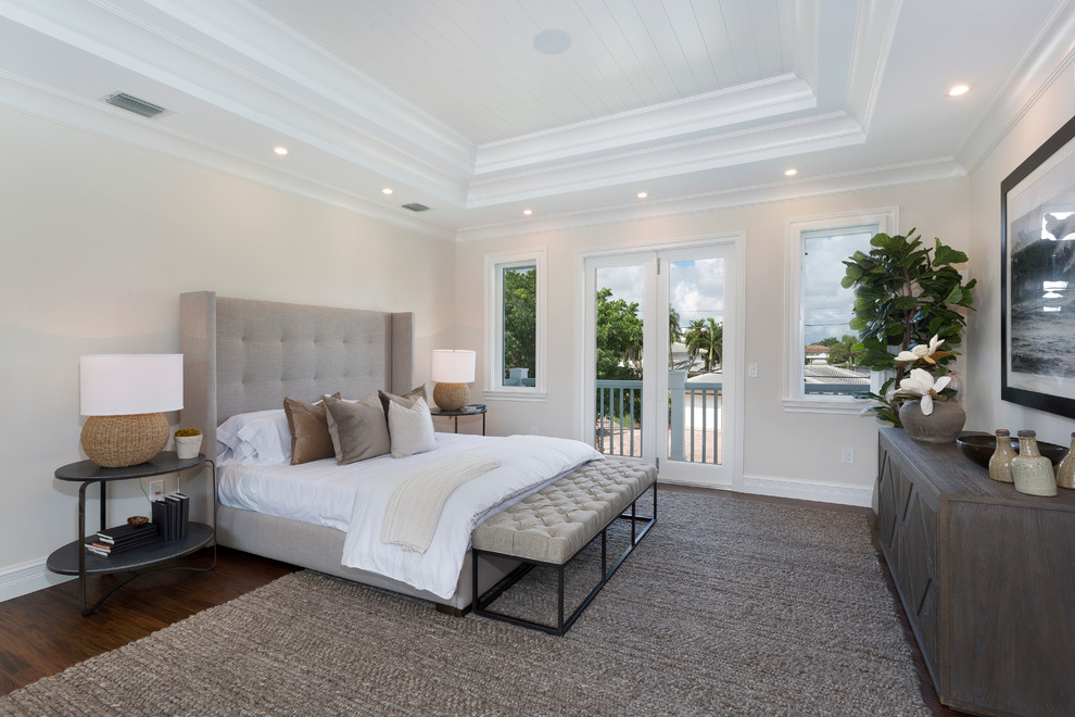 This is an example of a large beach style master bedroom in Other with beige walls, dark hardwood floors, no fireplace and brown floor.