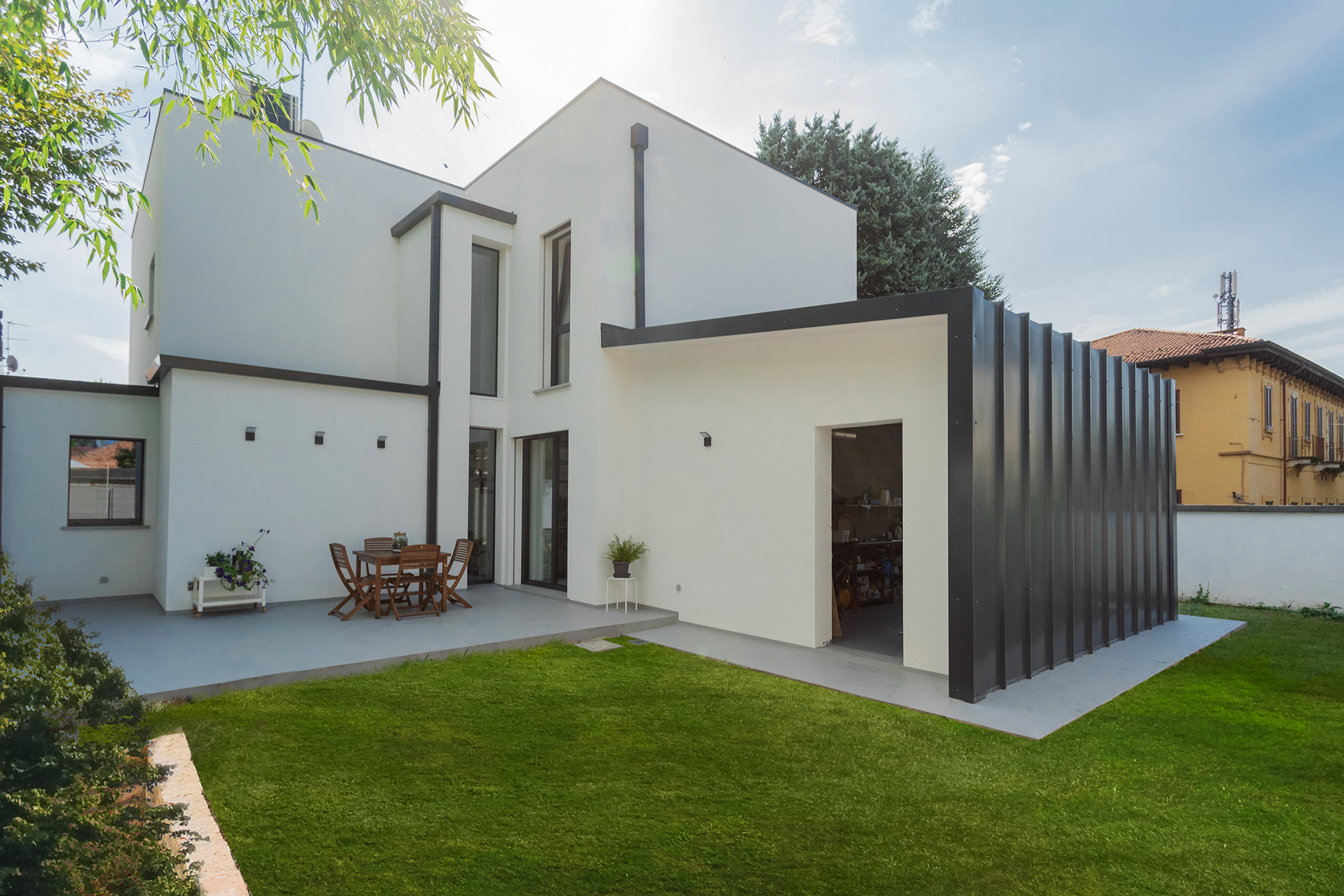 Immagine della villa bianca contemporanea a due piani di medie dimensioni con rivestimenti misti, tetto piano, copertura in metallo o lamiera e tetto grigio