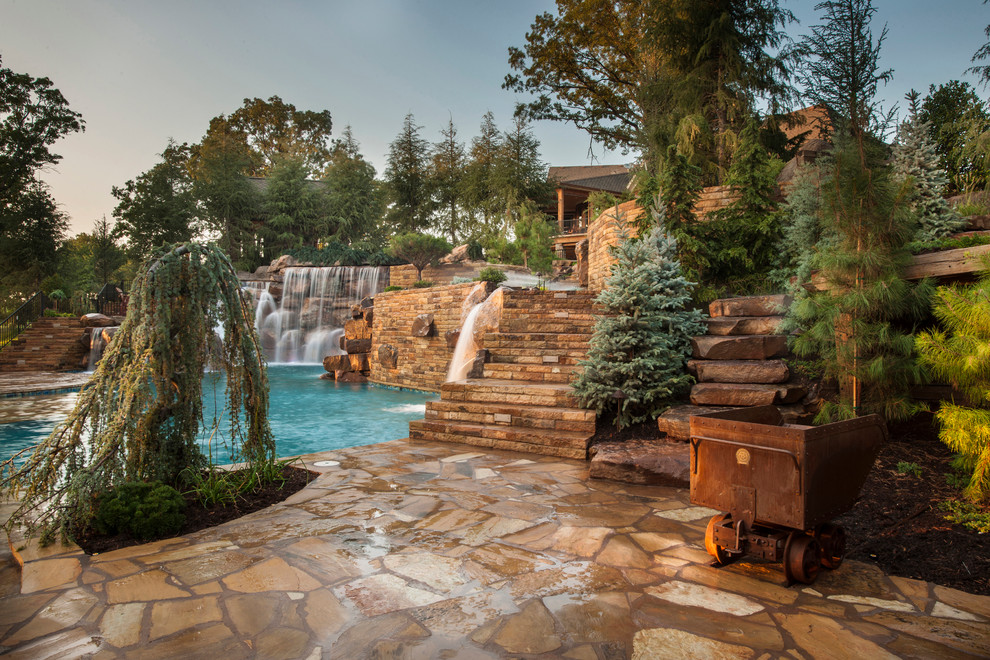 Design ideas for an expansive country backyard custom-shaped natural pool in Oklahoma City with a water feature and natural stone pavers.