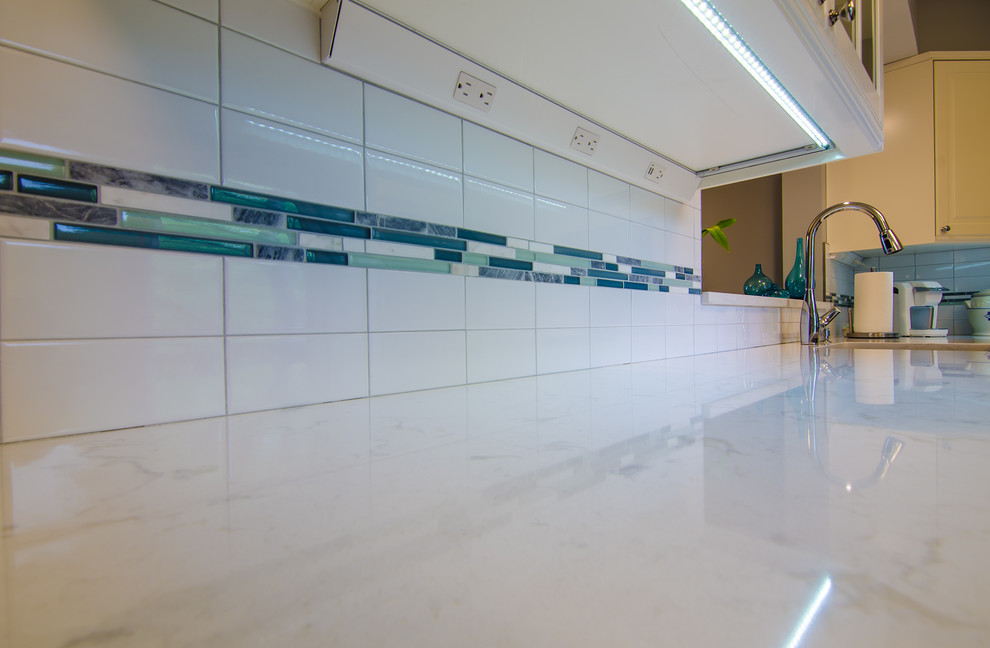 Mid-sized transitional l-shaped vinyl floor enclosed kitchen photo in DC Metro with an undermount sink, shaker cabinets, quartz countertops, white backsplash, ceramic backsplash, black appliances and no island
