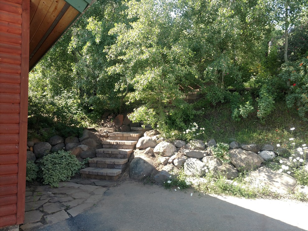 This is an example of a mid-sized country backyard shaded garden in Other with natural stone pavers.