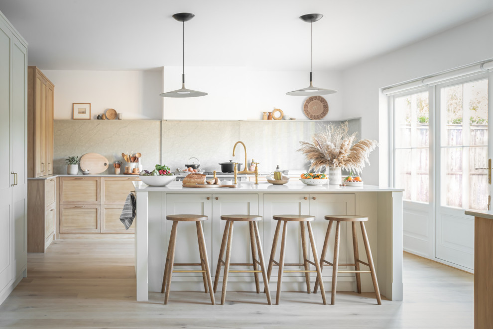 This is an example of a large scandi grey and cream kitchen/diner in Surrey with an integrated sink, shaker cabinets, light wood cabinets, quartz worktops, grey splashback, black appliances, light hardwood flooring, an island and grey worktops.