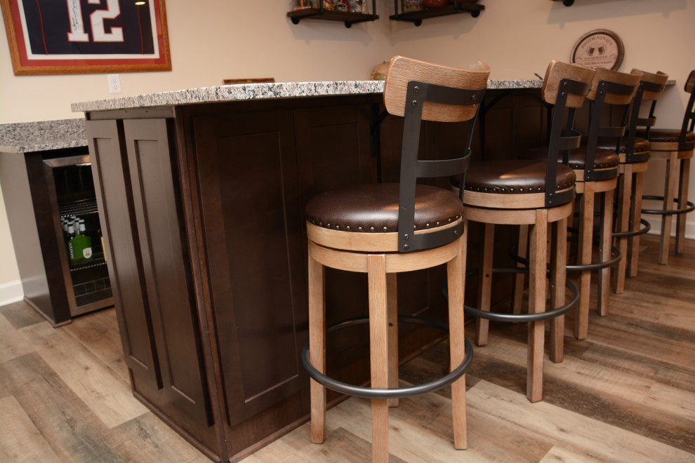 Mid-sized traditional single-wall seated home bar in DC Metro with an undermount sink, recessed-panel cabinets, dark wood cabinets, granite benchtops, brown floor and grey benchtop.