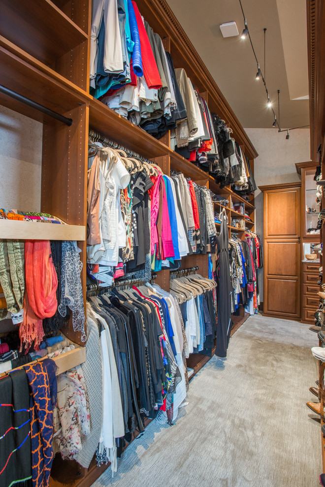 Inspiration for an expansive traditional gender-neutral walk-in wardrobe in Denver with raised-panel cabinets, medium wood cabinets, carpet and beige floor.