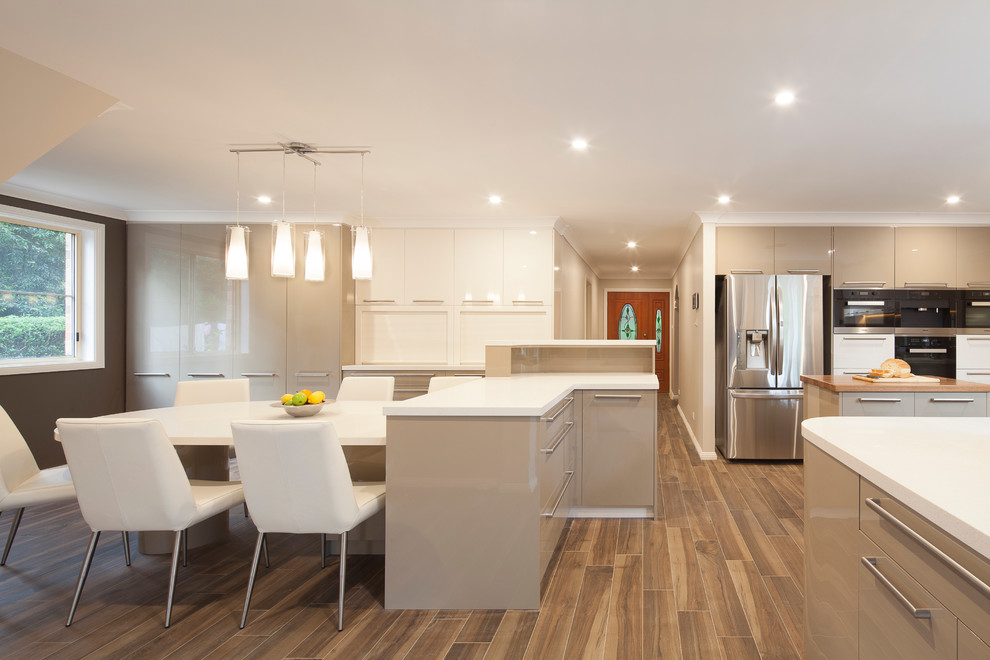 Design ideas for an expansive contemporary u-shaped eat-in kitchen in Sydney with an undermount sink, flat-panel cabinets, green cabinets, quartz benchtops, brown splashback, glass sheet splashback, stainless steel appliances, ceramic floors and multiple islands.