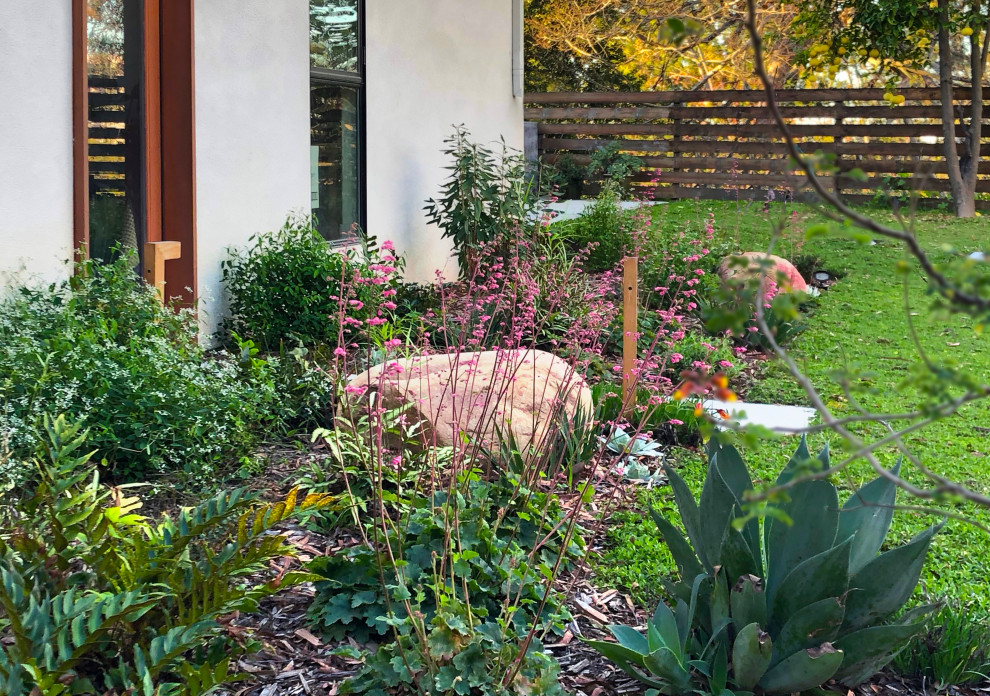 Großer, Schattiger Moderner Garten im Frühling, hinter dem Haus mit Betonboden, Metallzaun und Blumenbeet