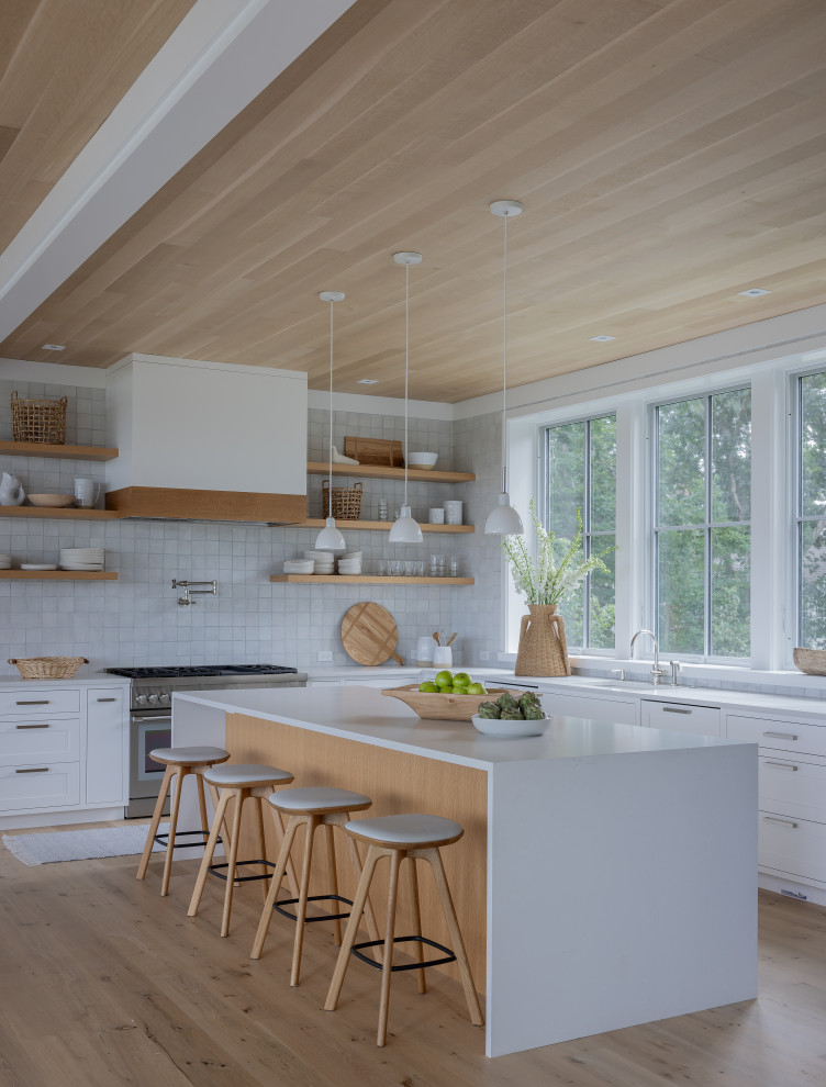 Beach style l-shaped kitchen in Boston with a submerged sink, shaker cabinets, white cabinets, grey splashback, stainless steel appliances, light hardwood flooring, an island, beige floors, white worktops and a wood ceiling.