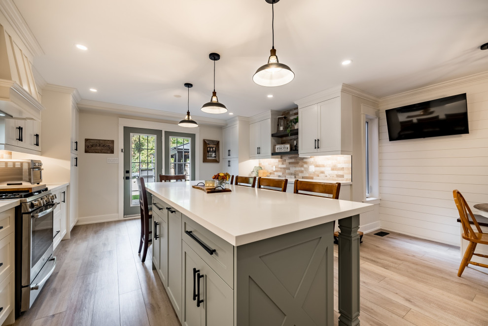 Large farmhouse l-shaped kitchen/diner in DC Metro with a belfast sink, shaker cabinets, white cabinets, engineered stone countertops, red splashback, brick splashback, stainless steel appliances, medium hardwood flooring, an island, yellow floors and white worktops.