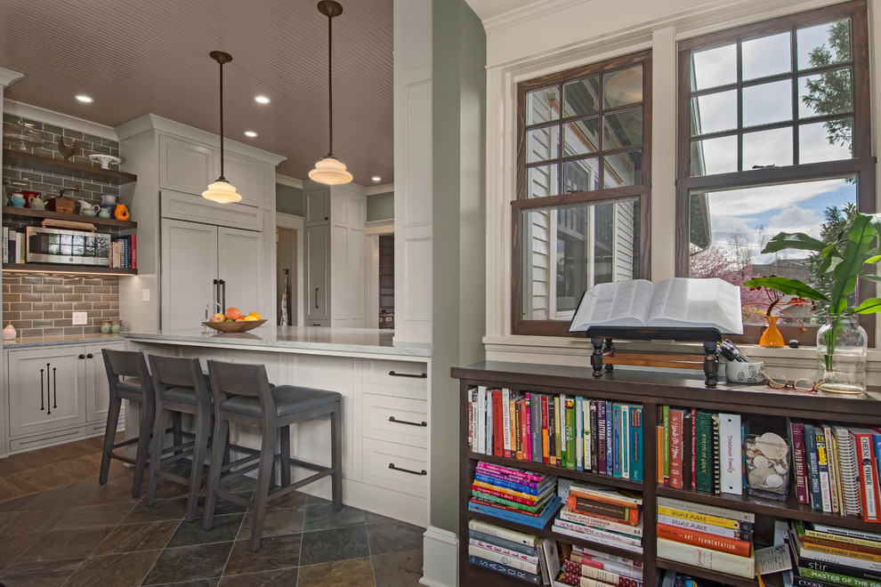 Inspiration for a mid-sized transitional u-shaped medium tone wood floor and brown floor enclosed kitchen remodel in Seattle with an undermount sink, beaded inset cabinets, gray cabinets, quartzite countertops, gray backsplash, ceramic backsplash, paneled appliances and a peninsula