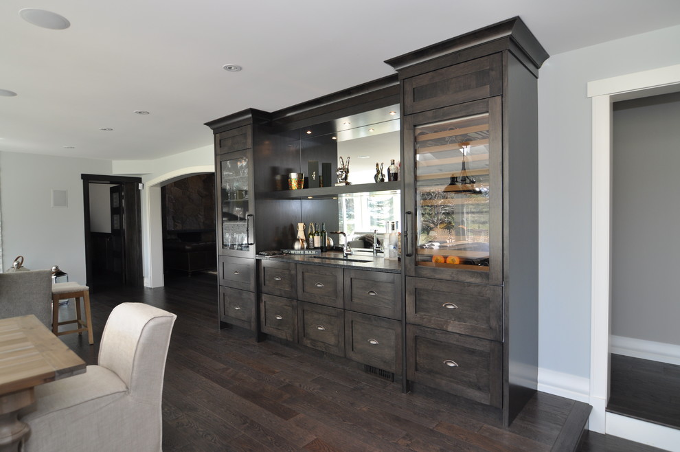 Photo of a large traditional single-wall wet bar in Vancouver with an undermount sink, shaker cabinets, dark wood cabinets, marble benchtops, beige splashback, dark hardwood floors and mirror splashback.