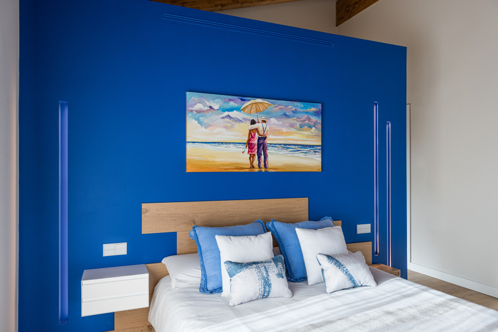 Réalisation d'une chambre parentale bohème de taille moyenne avec un mur bleu, un sol en bois brun, une cheminée ribbon, un manteau de cheminée en métal et un sol marron.