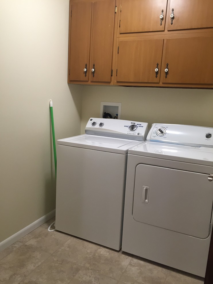 Photo of a small traditional single-wall dedicated laundry room in Columbus with flat-panel cabinets, medium wood cabinets, beige walls, ceramic floors and a side-by-side washer and dryer.