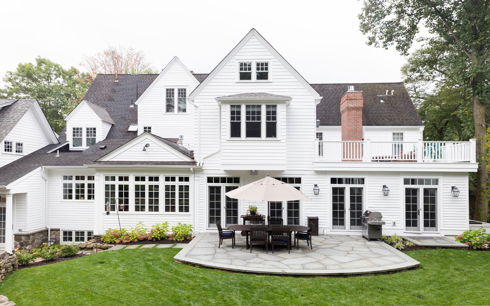 This is an example of a beach style white house exterior in New York with a shingle roof.