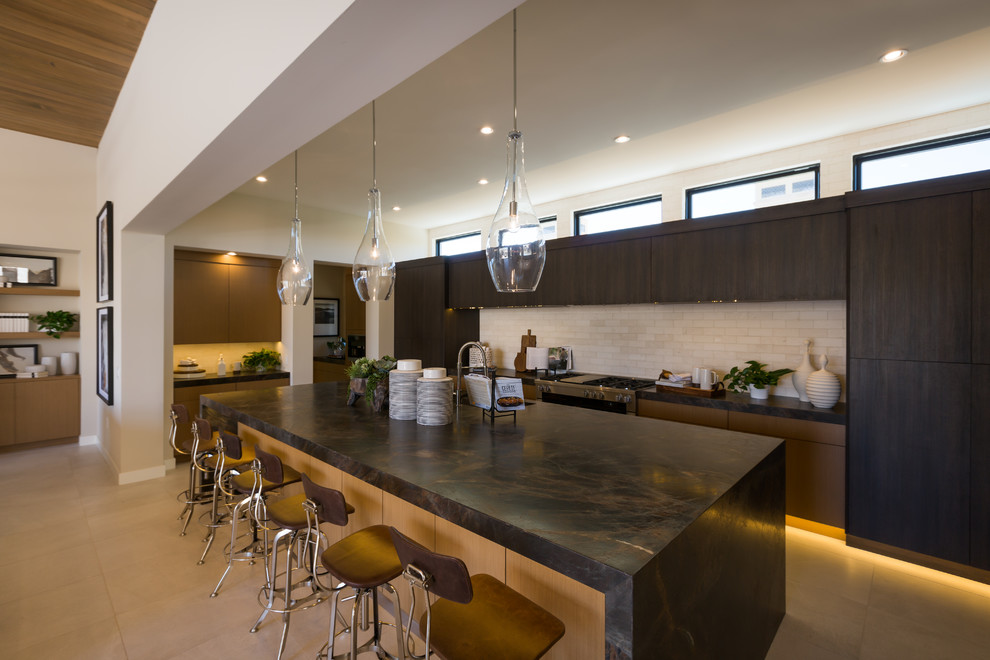 This is an example of a large modern open plan kitchen in Phoenix with an undermount sink, flat-panel cabinets, dark wood cabinets, beige splashback, stone tile splashback, panelled appliances, with island, beige floor and brown benchtop.