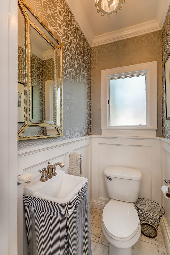 Photo of a small transitional powder room in Santa Barbara with a two-piece toilet, grey walls, marble floors, a pedestal sink, solid surface benchtops, white floor and white benchtops.