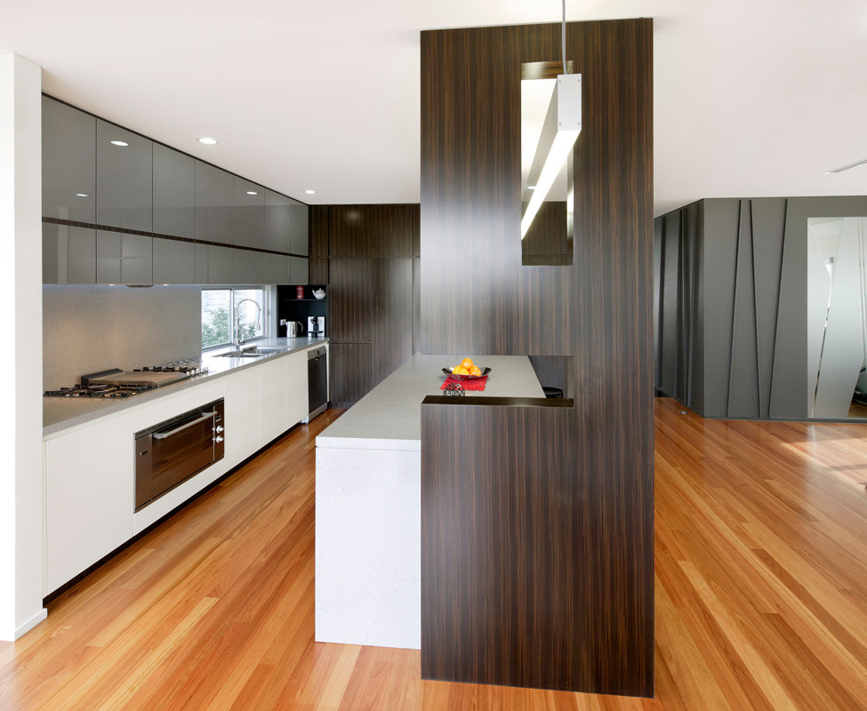 Photo of a mid-sized contemporary l-shaped eat-in kitchen in Sydney with an undermount sink, glass-front cabinets, quartz benchtops, stone slab splashback, dark wood cabinets, grey splashback, stainless steel appliances, medium hardwood floors and with island.