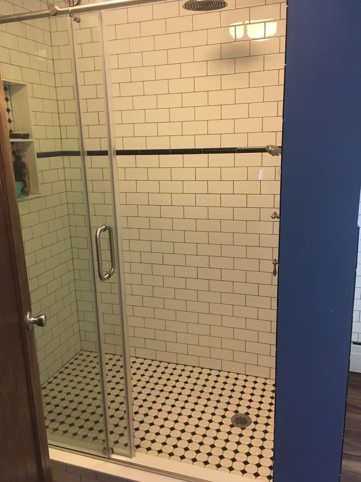 Small transitional kids bathroom in New York with an alcove shower, a two-piece toilet, black and white tile, ceramic tile, blue walls, linoleum floors, a pedestal sink, brown floor and a sliding shower screen.