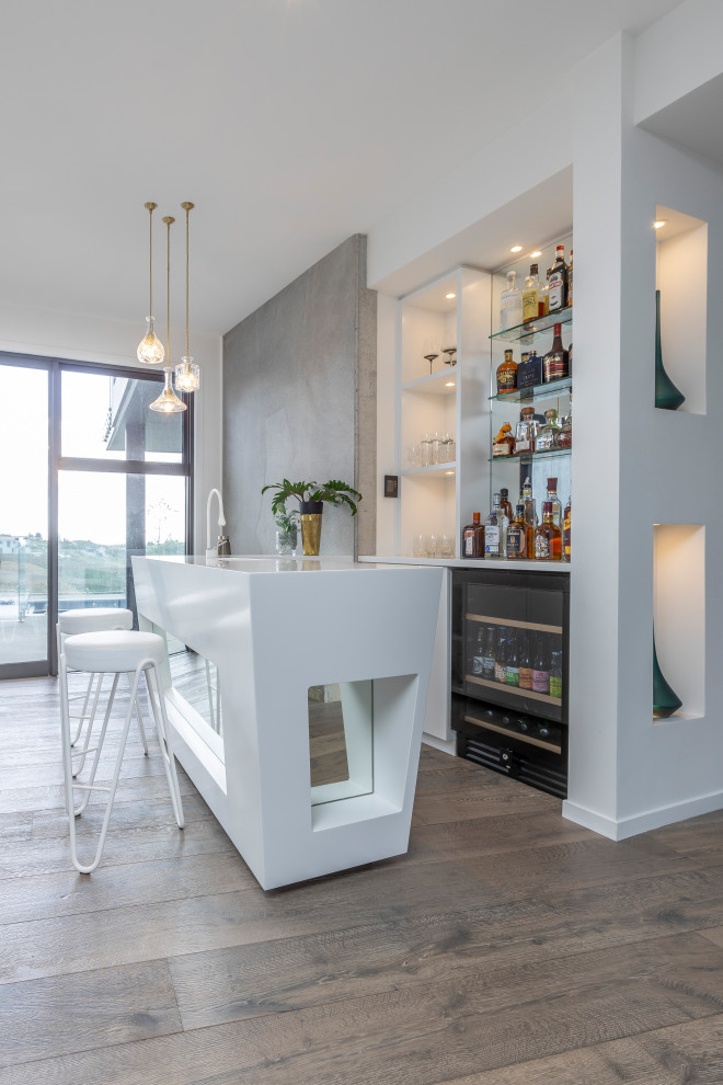 Photo of a large contemporary galley seated home bar in Auckland with an undermount sink, flat-panel cabinets, white cabinets, solid surface benchtops, mirror splashback, medium hardwood floors, brown floor and yellow benchtop.