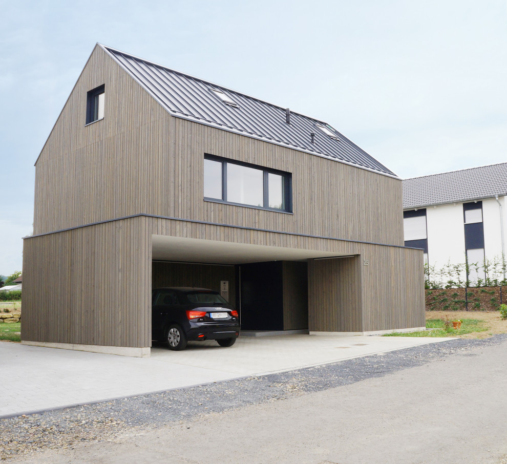 Modern two-storey house exterior in Frankfurt with wood siding, a gable roof, a metal roof, a black roof and clapboard siding.