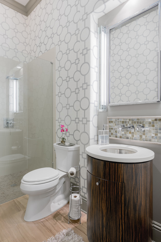 This is an example of a mid-sized transitional master bathroom in Tampa with flat-panel cabinets, dark wood cabinets, a curbless shower, a two-piece toilet, gray tile, white tile, multi-coloured walls, light hardwood floors, an undermount sink, porcelain tile, solid surface benchtops, beige floor and a hinged shower door.