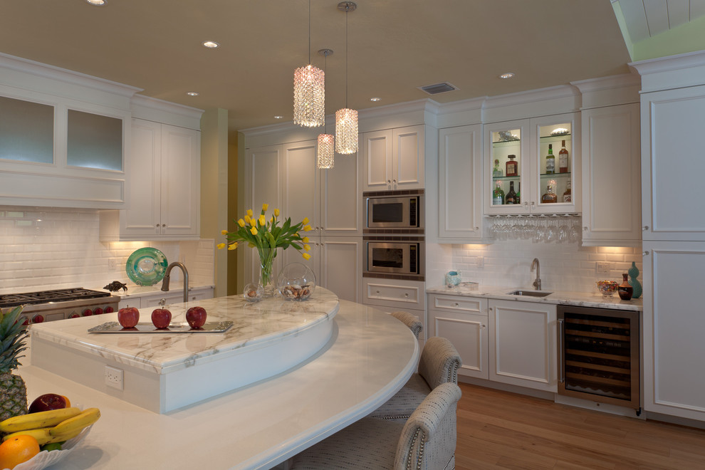 This is an example of a contemporary kitchen in Miami with raised-panel cabinets, white cabinets, white splashback, subway tile splashback and stainless steel appliances.