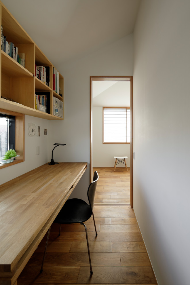 Design ideas for a mid-sized asian study room in Yokohama with white walls, medium hardwood floors, a built-in desk and beige floor.